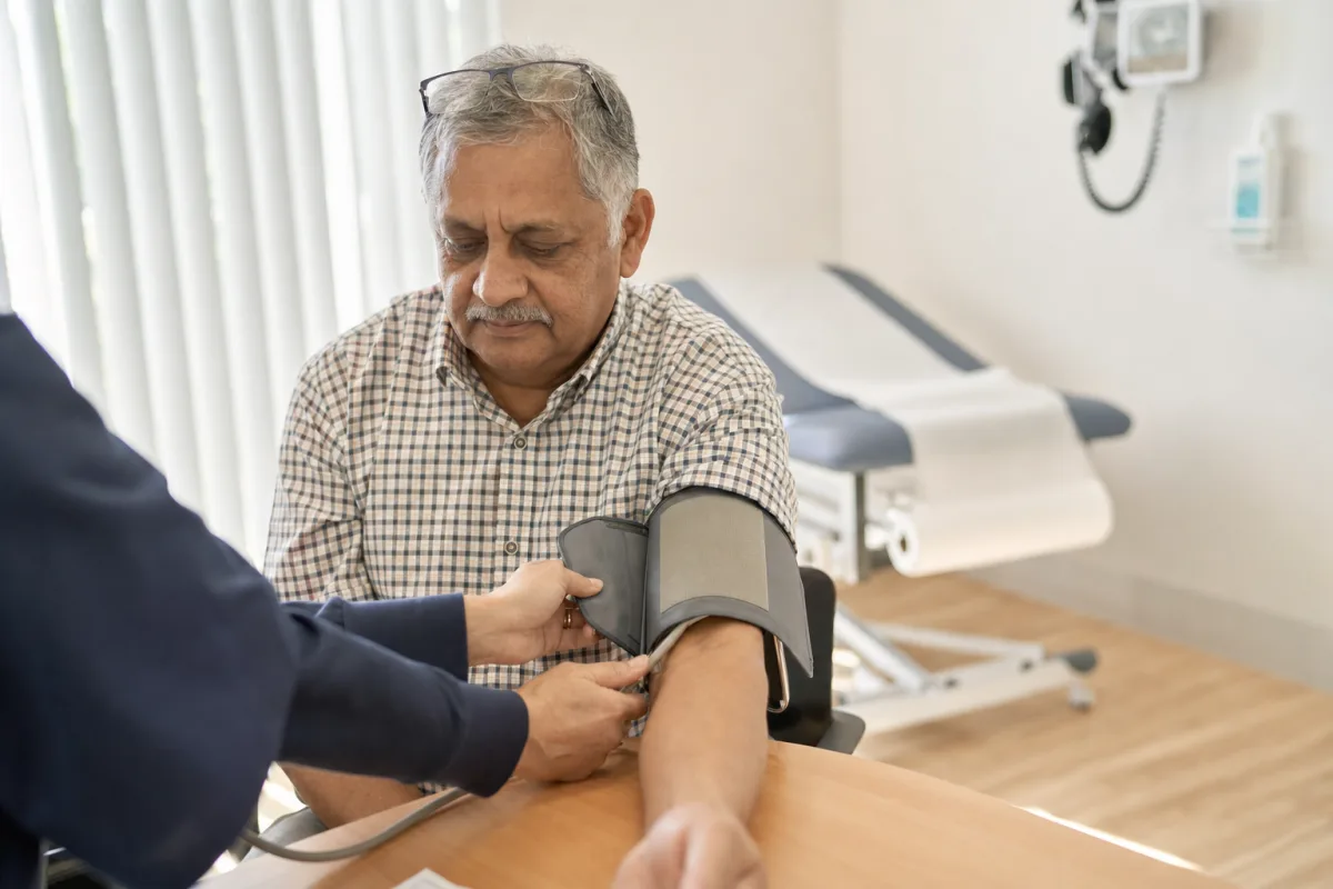 A blood pressure cuff being fitted to a patient's arm